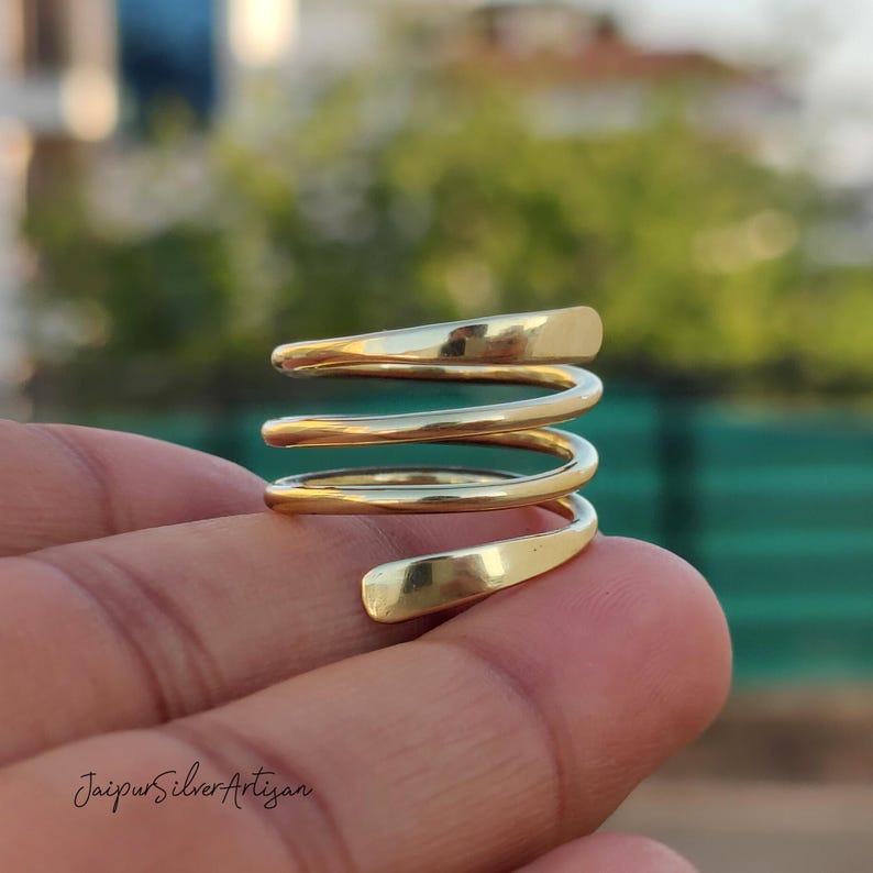 May include: Gold-toned spiral ring with four bands. The ring is made of metal and has a smooth, polished finish.