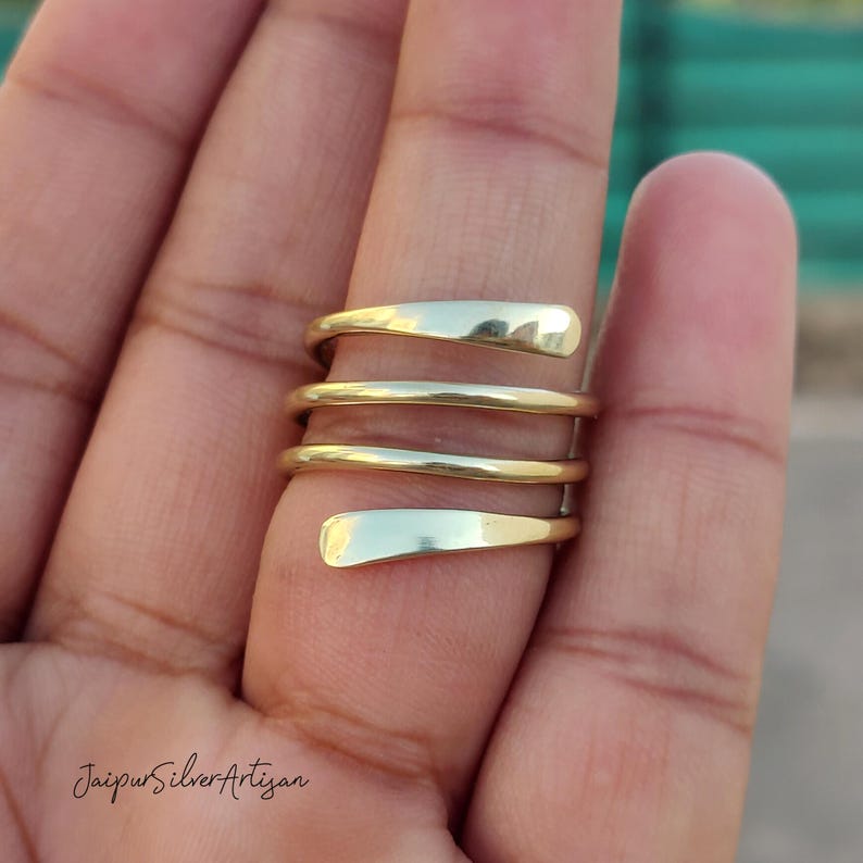May include: A gold-toned, multi-layered, spiral ring. The ring is made of thick, smooth metal and is designed to be worn on the finger.