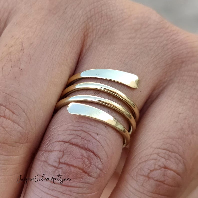 May include: A gold-toned spiral ring with a smooth, polished finish. The ring is made of multiple bands that wrap around the finger.