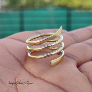 May include: A gold-toned spiral ring with multiple coils. The ring is made of metal and has a smooth, polished finish.