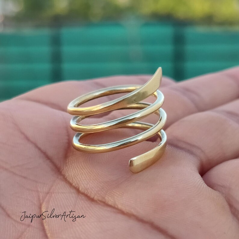 May include: A gold-toned spiral ring with multiple coils. The ring is made of metal and has a smooth, polished finish.