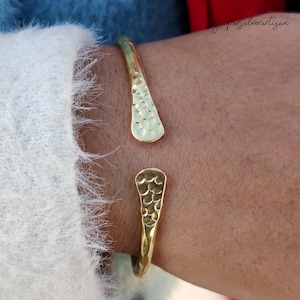May include: A gold hammered cuff bracelet with a unique teardrop design. The bracelet is open and adjustable to fit most wrists.