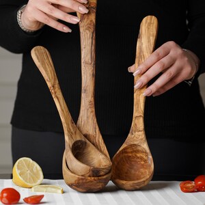 Puede incluir: Tres cucharones de madera de olivo, dos est&aacute;n anidados uno dentro del otro, todos son marrones con veta de madera natural.