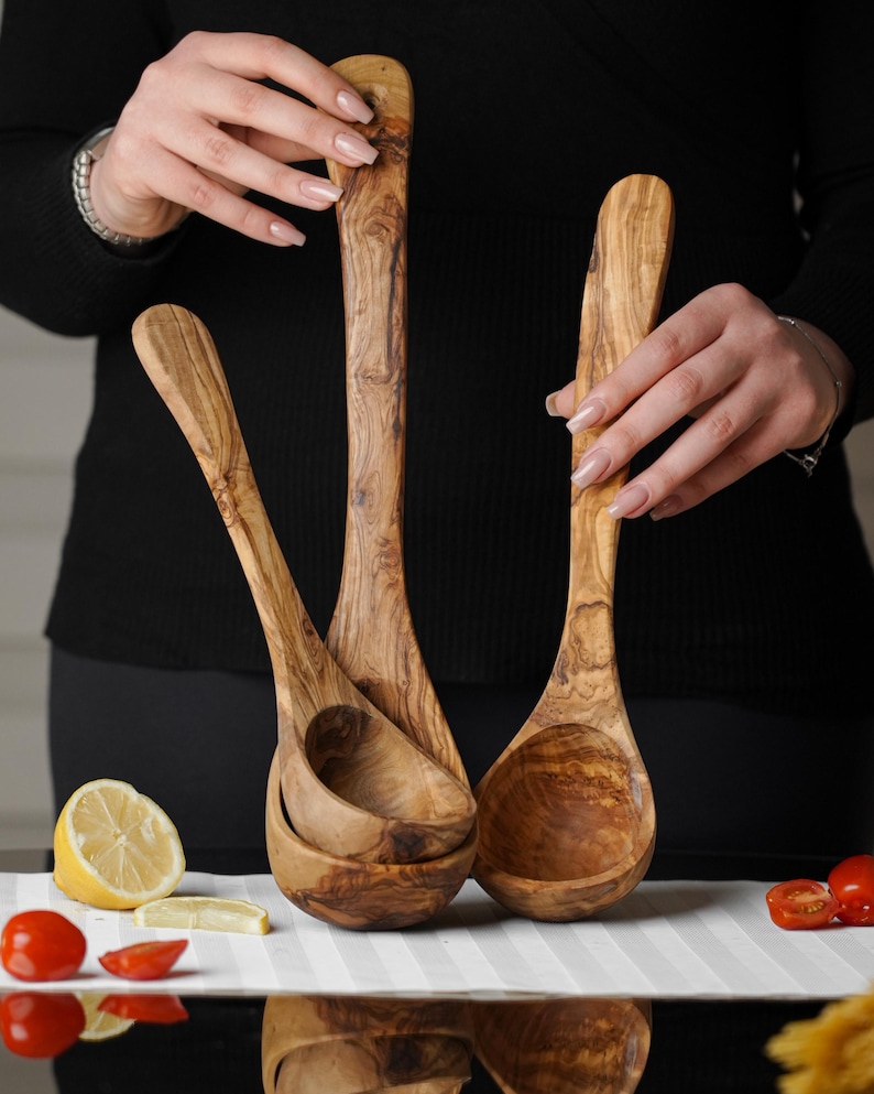 Puede incluir: Tres cucharones de madera de olivo, dos est&aacute;n anidados uno dentro del otro, todos son marrones con veta de madera natural.