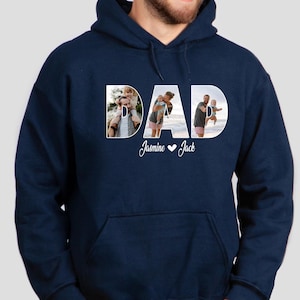 May include: Navy blue hooded sweatshirt with the word "DAD" spelled out in white letters. Each letter is filled with a photo of a person. The text "Jasmine &hearts; Jack" is printed below the word "DAD".