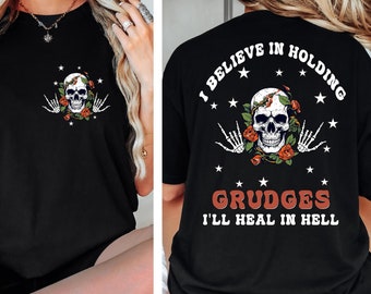 May include: Black t-shirt with a skull and roses graphic on the front and the text "I believe in holding grudges I'll heal in hell" on the back.