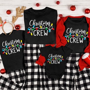 Puede incluir: Camisetas negras de Christmas Crew y un body para beb&eacute; con dise&ntilde;o de luces de colores. Las camisetas se combinan con pantalones de pijama a cuadros blancos y negros. Adornos navide&ntilde;os rojos y cuernos de reno completan el tema festivo.