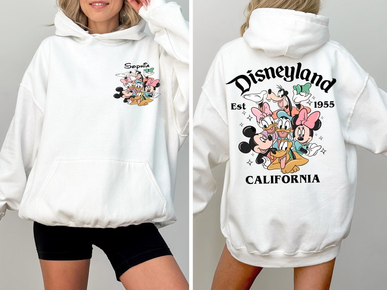 May include: White hoodie with a graphic of Mickey Mouse and friends on the front and a Disneyland logo with the text "Est 1955 California" on the back.