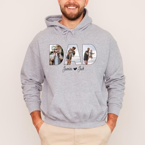 May include: A grey hooded sweatshirt with the word "DAD" printed on the front. The letters are filled with photos of a father and his children. The text "Jasmine &hearts; Jack" is printed below the word "DAD".
