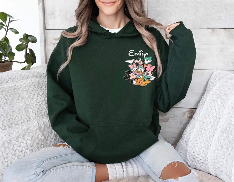 May include: A dark green hooded sweatshirt with a pocket and a graphic of Mickey Mouse and friends. The text "Emily" is printed on the sweatshirt.