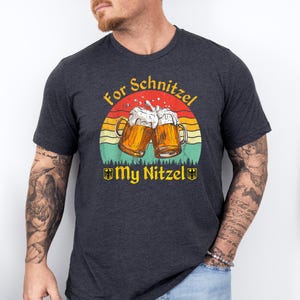 K&ouml;nnte beinhalten: Ein dunkelgraues T-Shirt mit einem Retro-Grafikdruck von zwei Bierkr&uuml;gen, die ansto&szlig;en, einem Sonnenuntergang und dem Text "For Schnitzel My Nitzel".