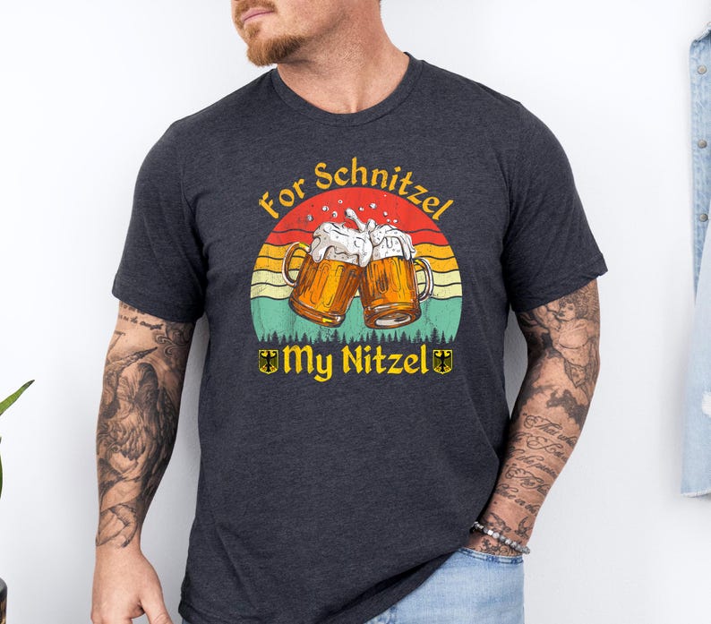 K&ouml;nnte beinhalten: Ein dunkelgraues T-Shirt mit einem Retro-Grafikdruck von zwei Bierkr&uuml;gen, die ansto&szlig;en, einem Sonnenuntergang und dem Text "For Schnitzel My Nitzel".