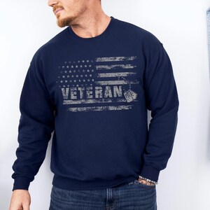Peut inclure: Sweat-shirt bleu marine avec un motif de drapeau am&eacute;ricain vieilli et le mot "Veteran" en blanc.