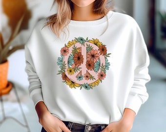 May include: White sweatshirt with a peace sign surrounded by colorful flowers. The peace sign is pink and the flowers are yellow, orange, red, blue, and green.