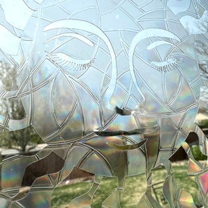 May include: A close-up of a frosted glass window with a decorative design of a woman's face. The design is etched into the glass, creating a subtle, iridescent effect.