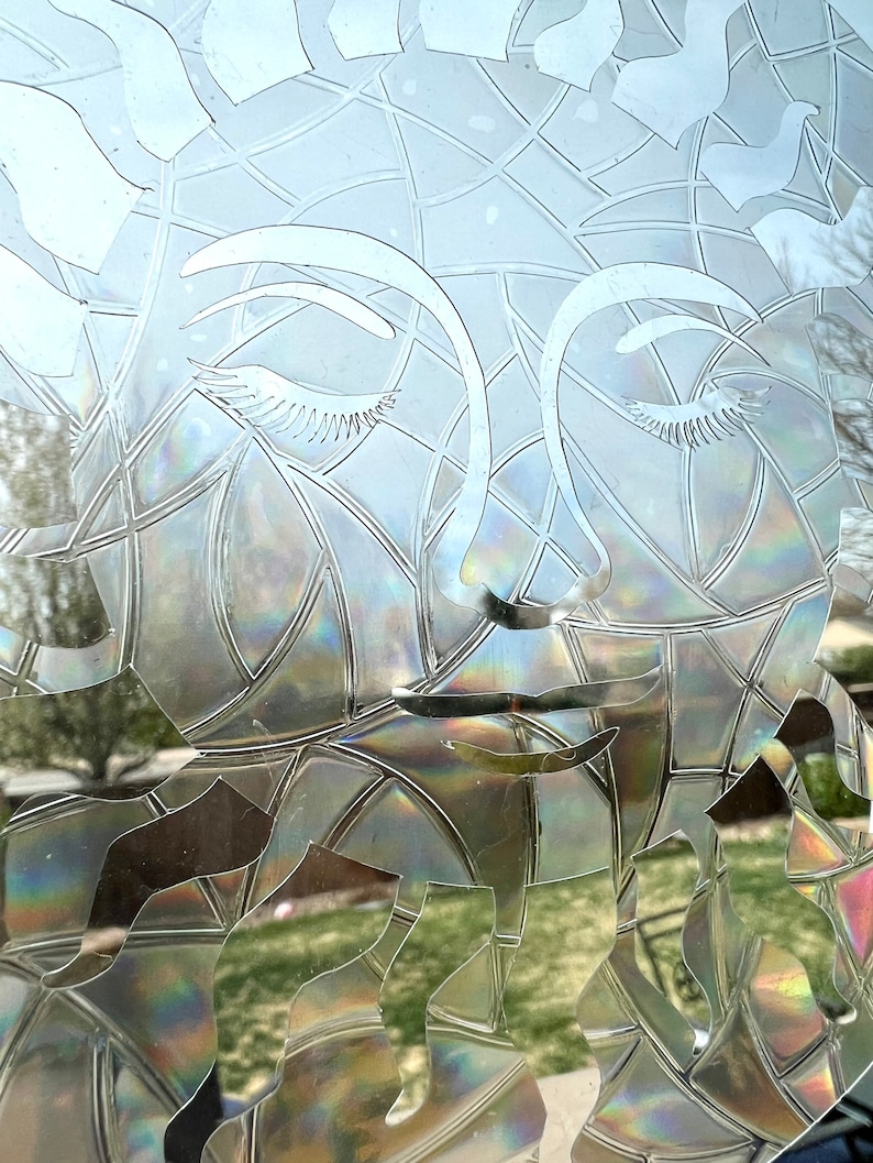 May include: A close-up of a frosted glass window with a decorative design of a woman's face. The design is etched into the glass, creating a subtle, iridescent effect.