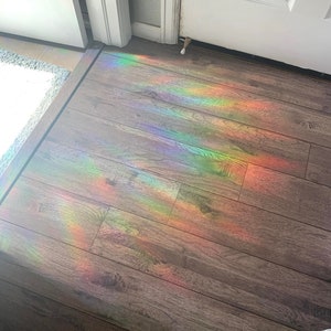 May include: A rainbow prism effect is cast on a wooden floor, creating a colorful display of light.