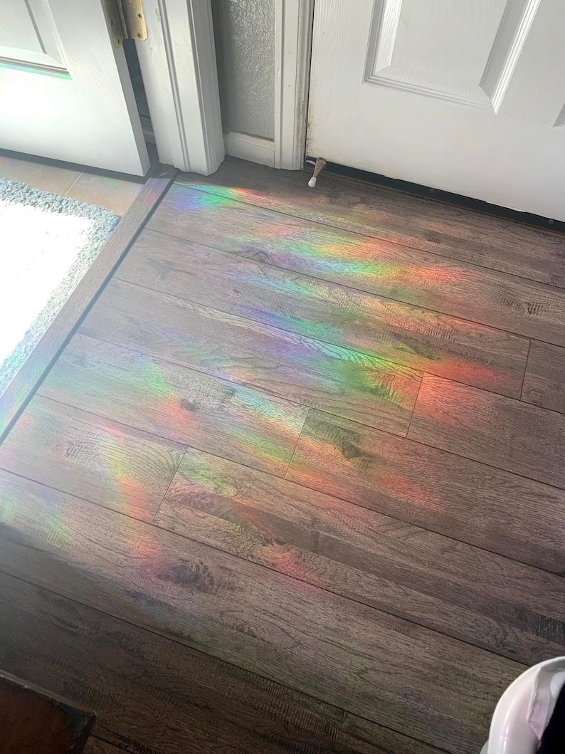 May include: A rainbow prism effect is cast on a wooden floor, creating a colorful display of light.
