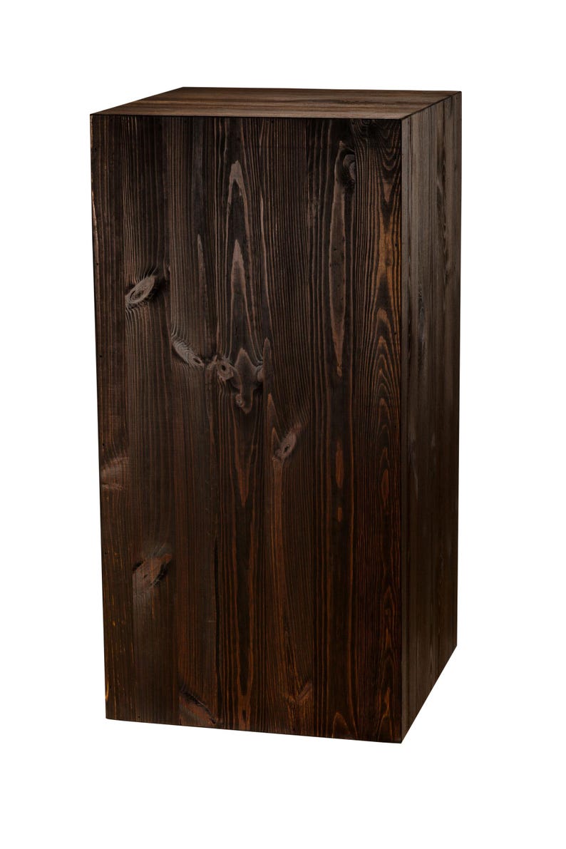 May include: A dark brown wooden cube, possibly a stool or a decorative piece. The wood grain is visible and the surface is smooth.