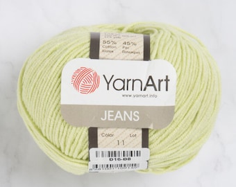 May include: A skein of light green YarnArt Jeans yarn. The label indicates the yarn is 55% cotton and 45% Pac. The label also includes the word "JEANS", the color number 11, and the code D16-D8.