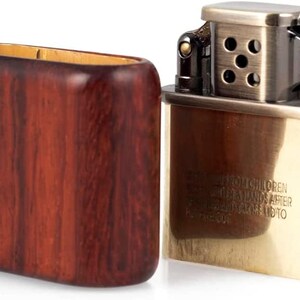 May include: A vintage-style lighter with a brass finish and a wooden case. The lighter has a safety warning that reads "Keep out of reach of children.  Keep away from hands after filling.  Close lid to prevent fire."