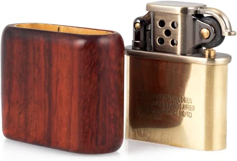 May include: A vintage-style lighter with a brass finish and a wooden case. The lighter has a safety warning that reads "Keep out of reach of children.  Keep away from hands after filling.  Close lid to prevent fire."