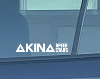 Può includere: Una sezione di un'auto blu scuro con un portapacchi e il testo "YAKIMA" visibile. Il finestrino dell'auto mostra il testo "AKINA SPEED STARS". La maniglia della portiera dell'auto è argentata.