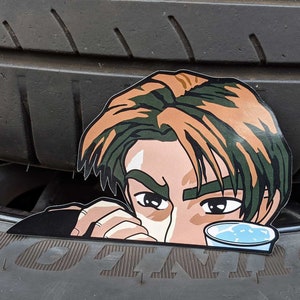 Op de afbeelding: Een sticker van een cartoonman met bruin haar en groene ogen, die drinkt uit een blauwe beker. De sticker is geplaatst op een zwarte band.