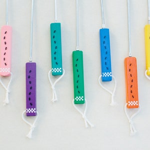 May include: Nine wooden sticks with strings attached to the bottom. Each stick is painted a different color: red, pink, purple, green, blue, orange, yellow, white, and black. Each stick has a row of black ants painted on it.