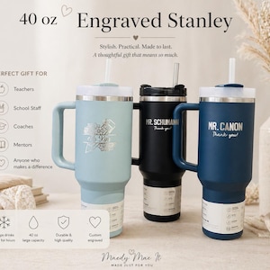 May include: Three 40 oz engraved Stanley tumblers in light blue, black, and navy blue. Each tumbler has a handle, a white lid, and a straw. The light blue tumbler has a floral design and the name "K. Kin". The black tumbler has "MR. SCHUMANN" and the navy blue tumbler has "MR. CANON".