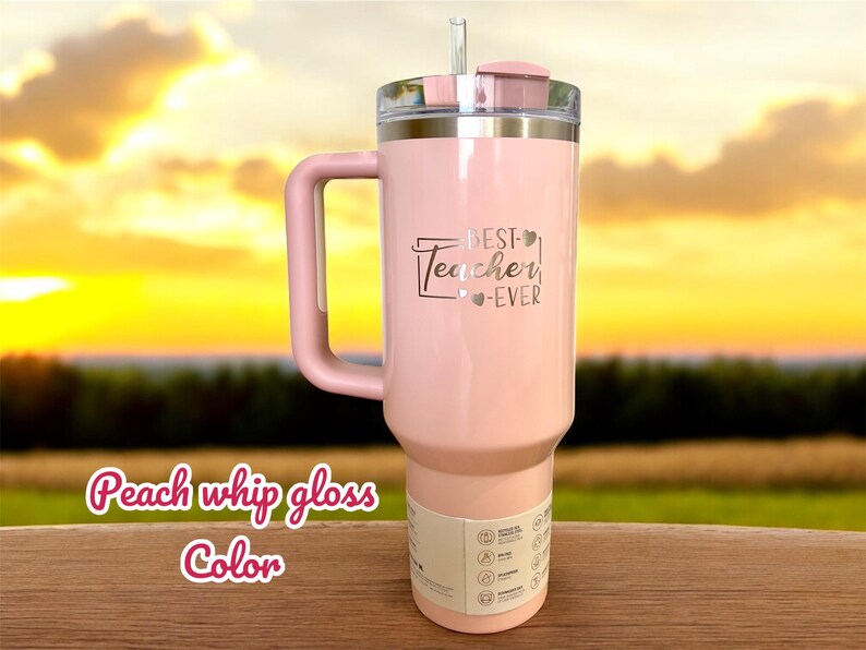 May include: A peach-colored tumbler with a handle, a clear lid, and a straw. The text "BEST Teacher EVER" is printed on the front. The words "Peach whip gloss Color" are written in a cursive font at the bottom.