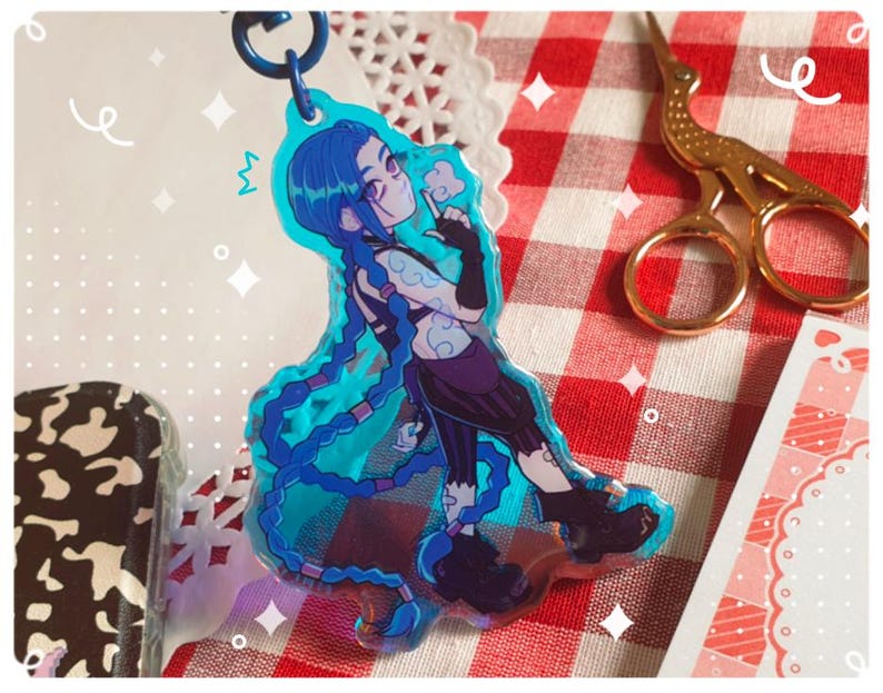 K&ouml;nnte beinhalten: Ein blau-violetter Acryl-Schl&uuml;sselanh&auml;nger mit einer Figur mit langen blauen Z&ouml;pfen. Die Figur tr&auml;gt ein schwarzes Outfit und h&auml;lt einen kleinen Gegenstand. Der Schl&uuml;sselanh&auml;nger ist an einem blauen Metallring befestigt.
