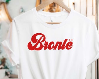 Pode incluir: Camiseta branca com um gráfico vermelho de estilo retrô que diz "Bronte"
