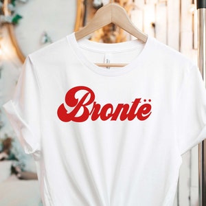 May include: White t-shirt with a red retro-style graphic that says "Bronte"