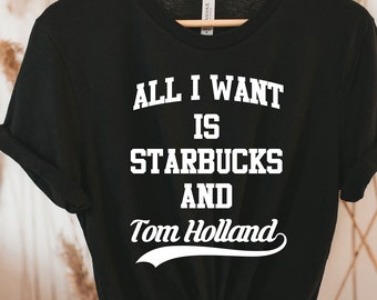May include: Black t-shirt with white text that reads "All I want is Starbucks and Tom Holland" in a retro font.