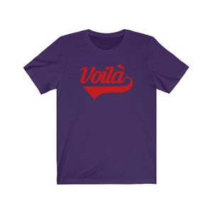 Puede incluir: Camiseta de manga corta de color morado con un gr&aacute;fico rojo "Voil&agrave;" en una fuente de b&eacute;isbol vintage.