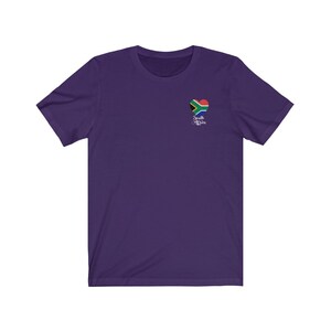 May include: Purple short-sleeved t-shirt with a heart-shaped South African flag graphic and the text "South Africa" in white cursive.