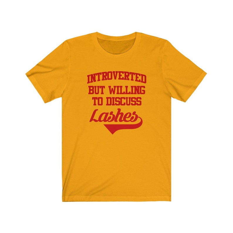May include: Yellow short-sleeved t-shirt with red text that reads "Introverted but willing to discuss Lashes".
