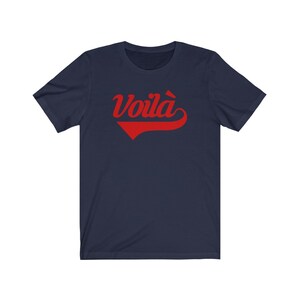 Puede incluir: Una camiseta azul marino con un gr&aacute;fico rojo "Voil&agrave;" en una fuente de b&eacute;isbol vintage.