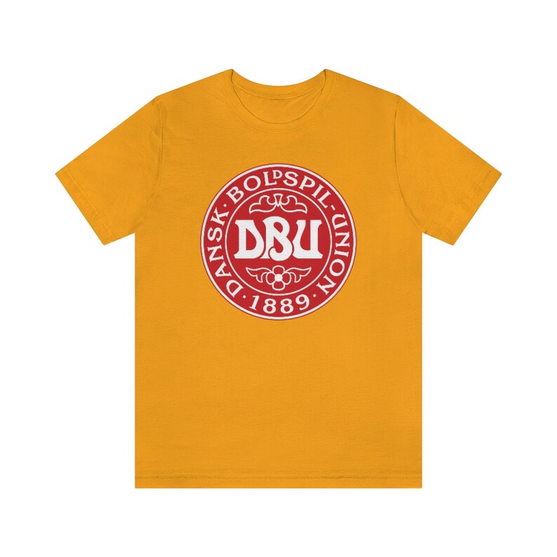 Puede incluir: Una camiseta amarilla con un logotipo rojo y blanco que dice "Dansk Boldspil-Union DBU 1889".