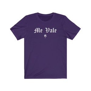 May include: Purple short-sleeved t-shirt with the text "Me Vale" in white gothic lettering and a small white rose graphic.