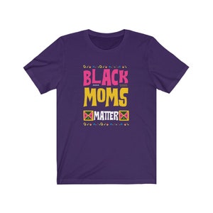 May include: Purple short-sleeved t-shirt with the text "Black Moms Matter" in yellow, pink, and black lettering. The text is surrounded by a colorful geometric pattern.