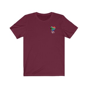 May include: Burgundy short-sleeved t-shirt with a heart-shaped South African flag graphic and the text "South Africa" underneath.