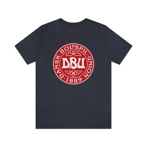 Puede incluir: Una camiseta azul marino con un logotipo circular rojo. El logotipo dice "Dansk Boldspil-Union DBU 1889" en texto blanco.