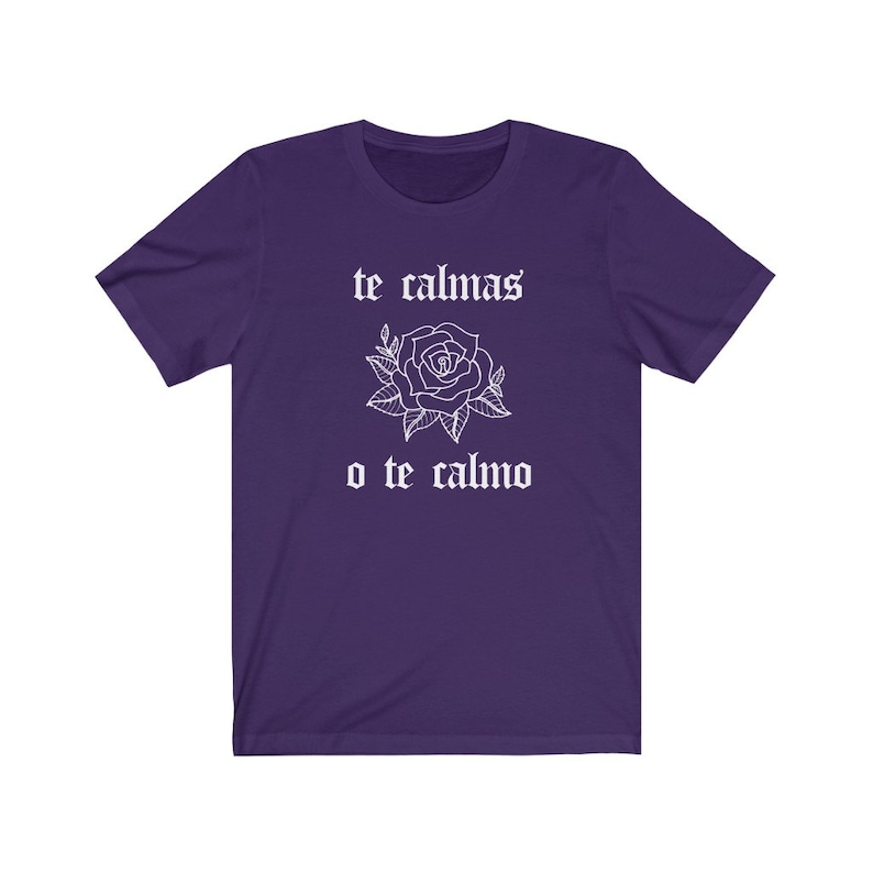 May include: Purple t-shirt with white text that reads "te calmas o te calmo" and a white rose graphic.