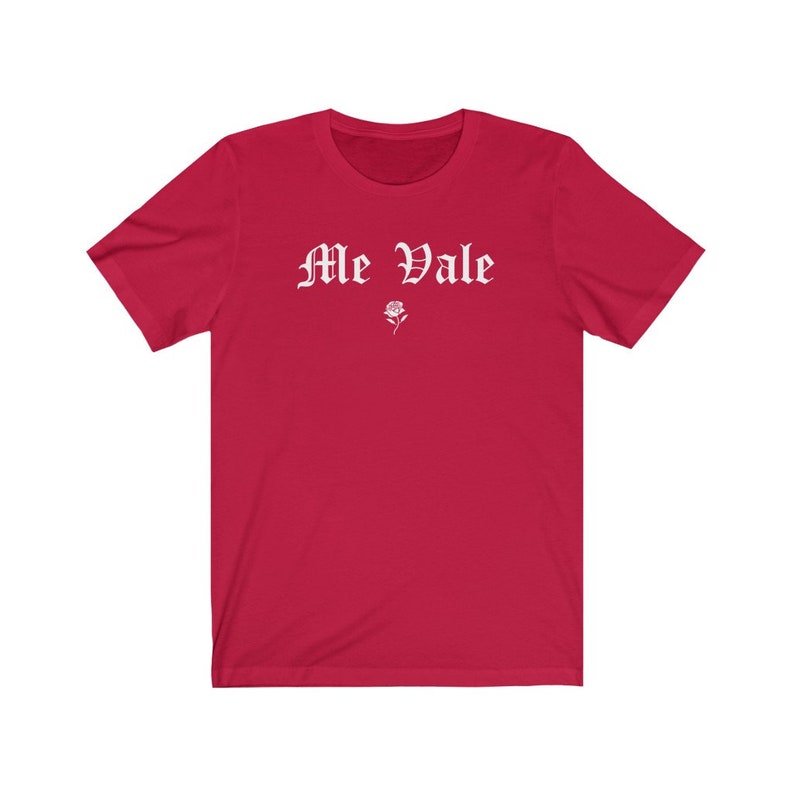 May include: Red short-sleeved t-shirt with white text that reads "Me Vale" in a gothic font. A small white rose is below the text.