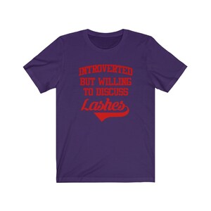 May include: Purple short-sleeved t-shirt with the text "Introverted but willing to discuss Lashes" in red.