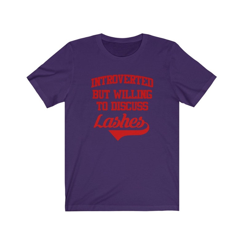 May include: Purple short-sleeved t-shirt with the text "Introverted but willing to discuss Lashes" in red.