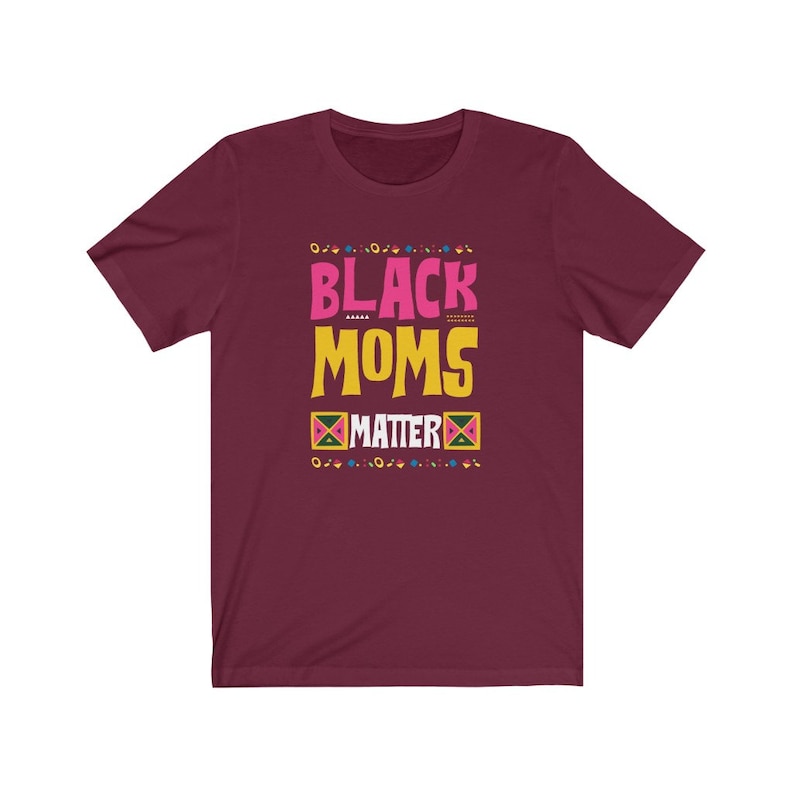 May include: Burgundy t-shirt with the text "Black Moms Matter" in pink, yellow, and black lettering. The text is surrounded by a colorful geometric pattern.