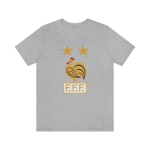 May include: A gray t-shirt with a gold rooster and two stars above it. The text "F.F.F." is below the rooster.